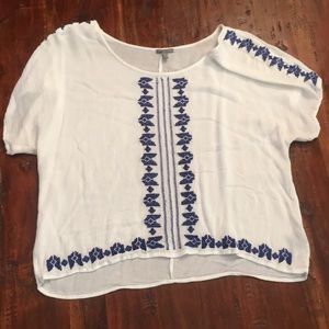 White boho top with blue embroidery.